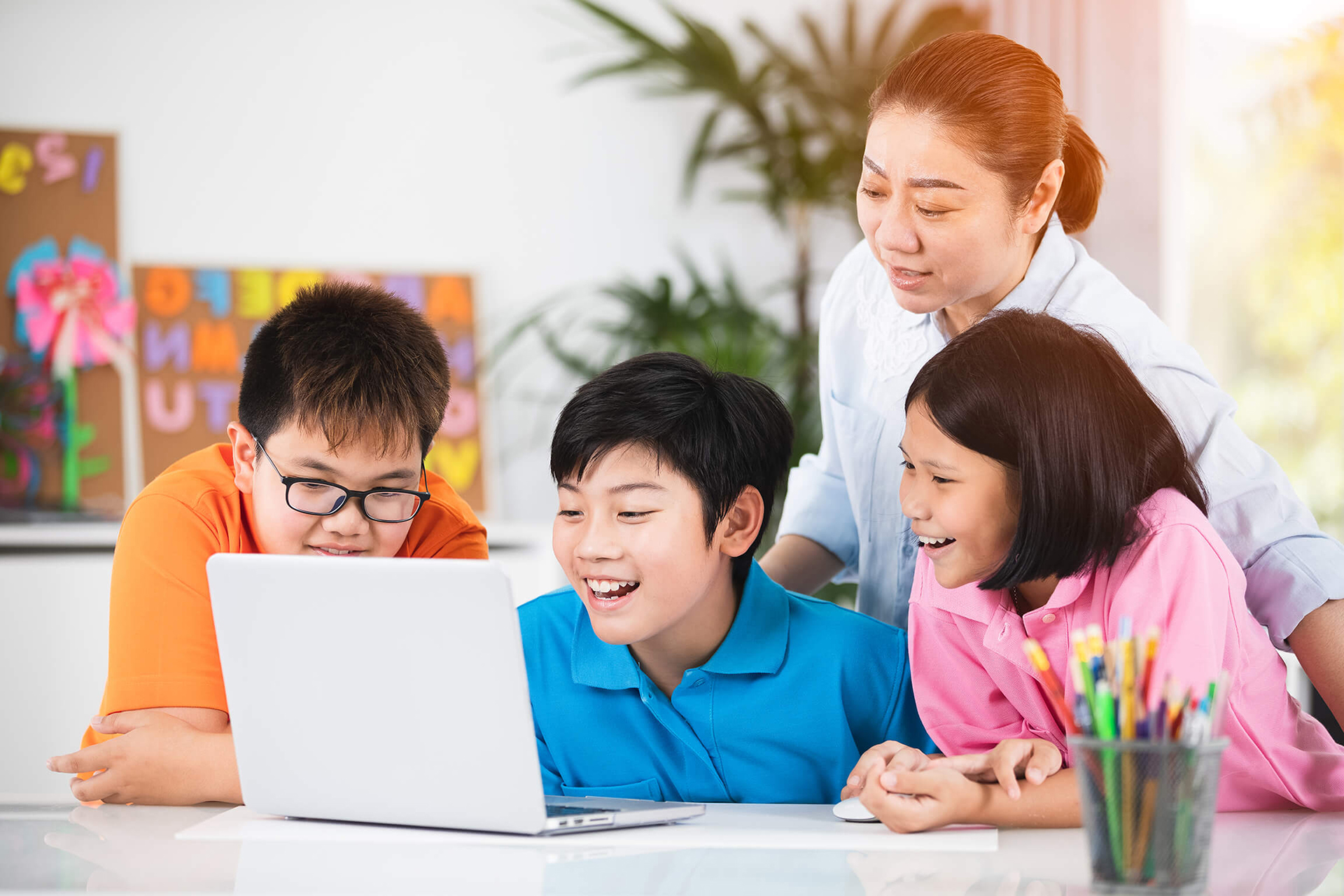 Teacher and cute asian children using laptop together